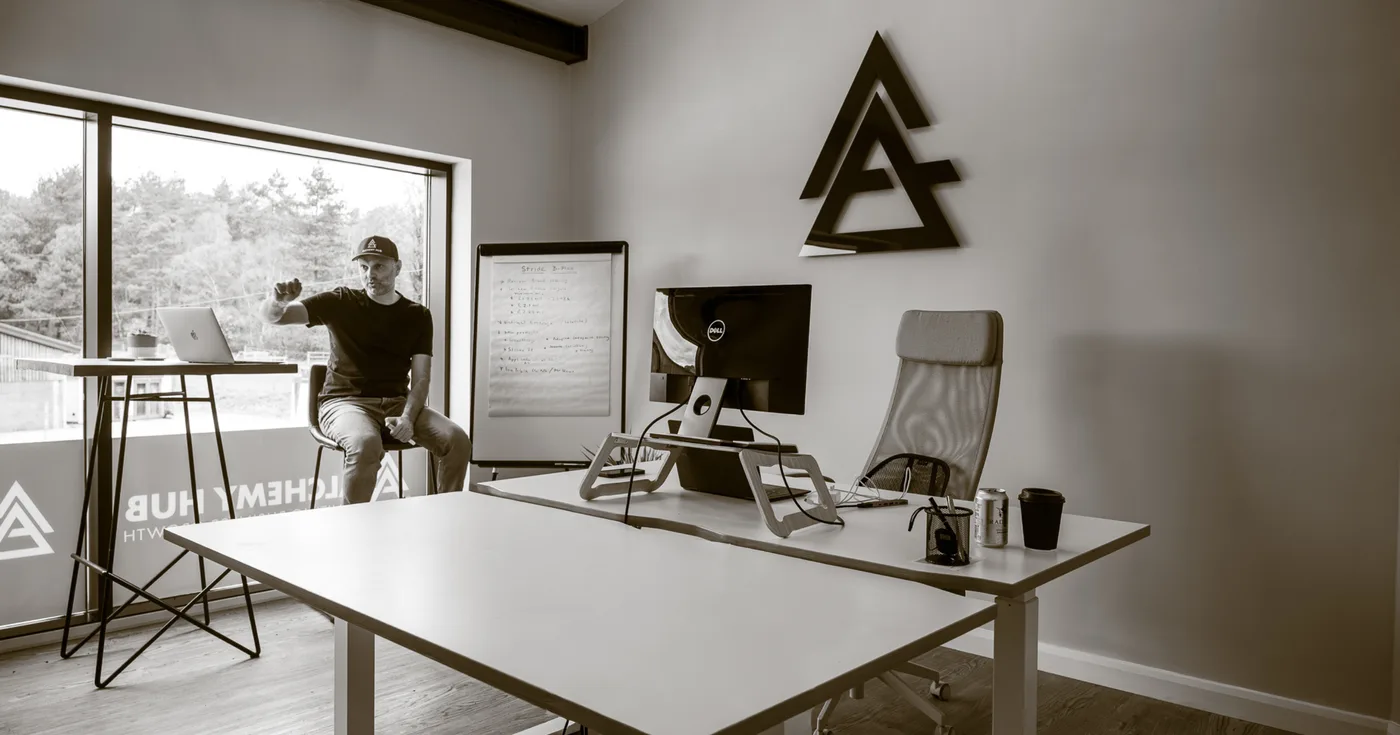 The Alchemy Hub office, the house mark mounted on the wall above a work table.