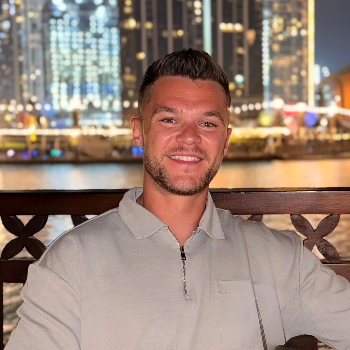 Erik Hudson on a terrace at night, the Dubai skyline lit behind him.