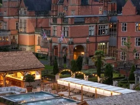 Hoar Cross Hall at dusk, its lit spa terrace and outdoor pools in the foreground.